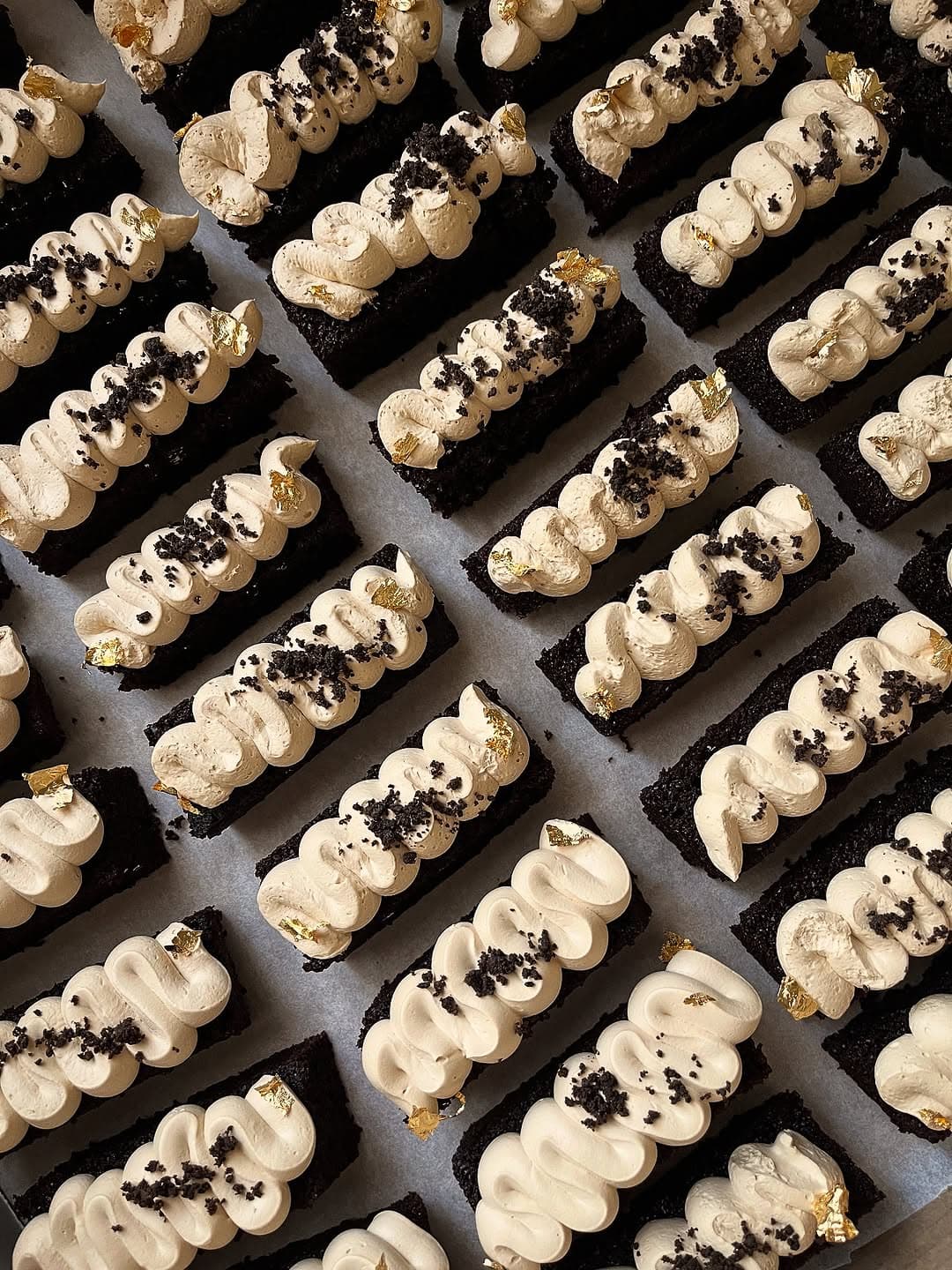 Piped chocolate eclairs with gold leaf at a tasting event